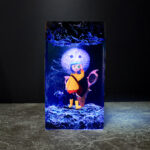 Detailed handmade Coraline Resin Lamp illuminating a dark room, a unique spooky decor piece for fans.